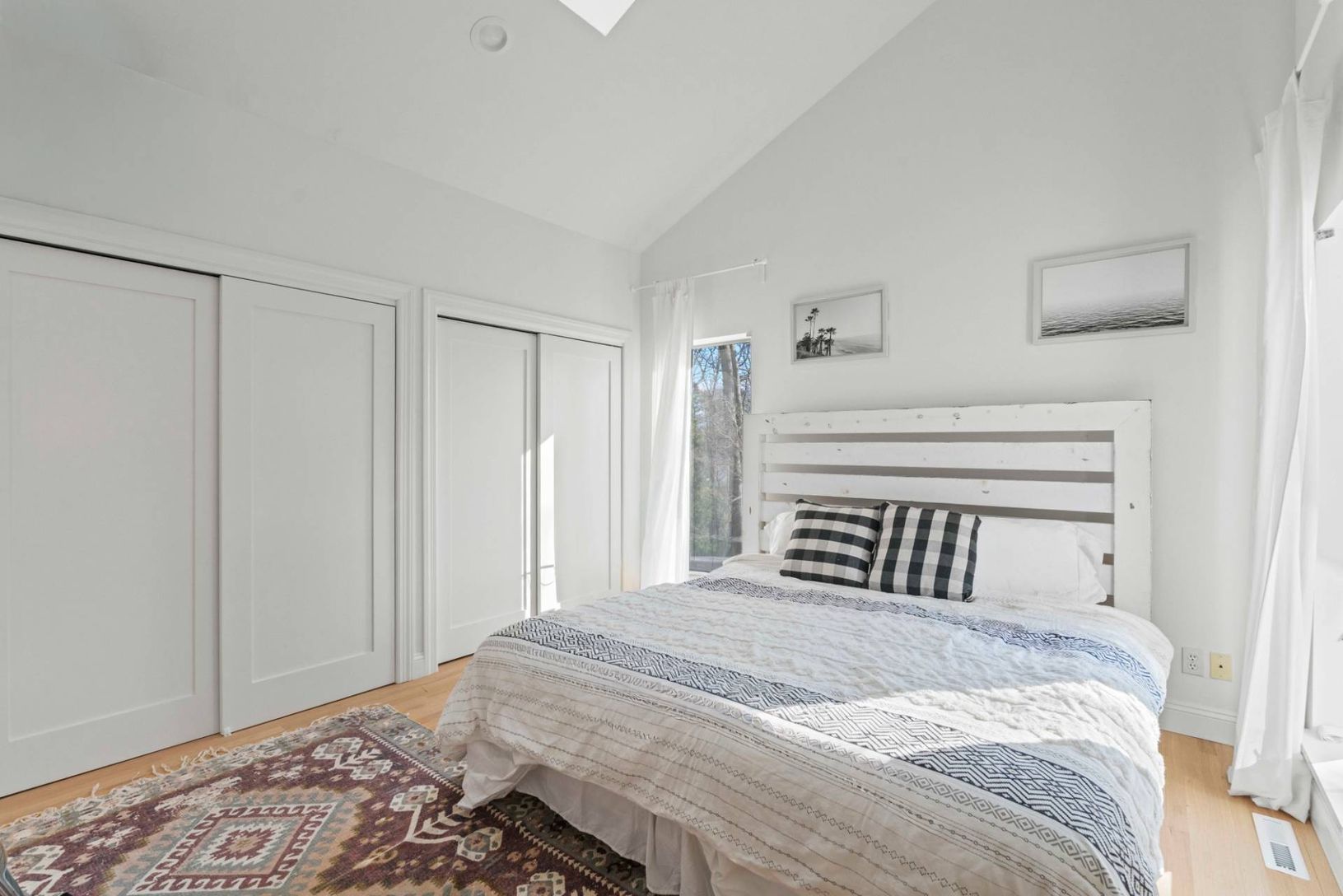 Guest Bed 2 of 5 featuring multiple closets, a skylight, high vaulted ceiling, and oak floors