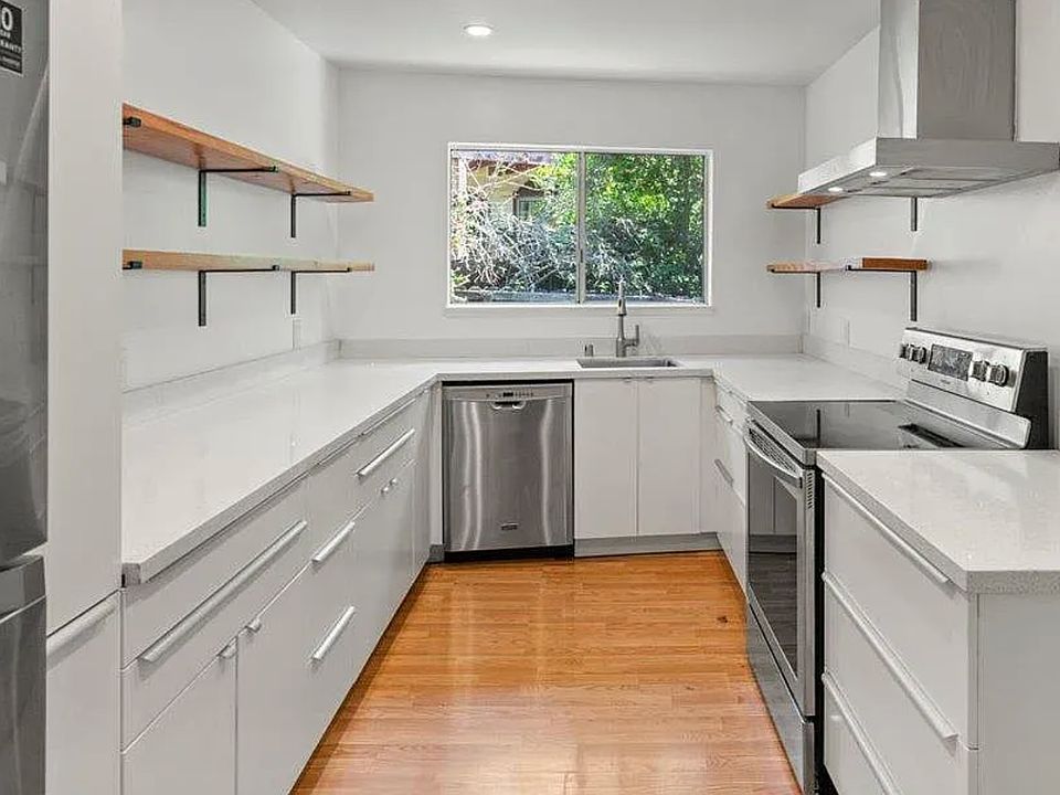 This bright, modern kitchen is a cook's dream _ sleek quartz countertops, stainless steel appliances, and plenty of prep space make it perfect for everyday meals or dinner parties. The open shelving adds allows for plenty of storage area.