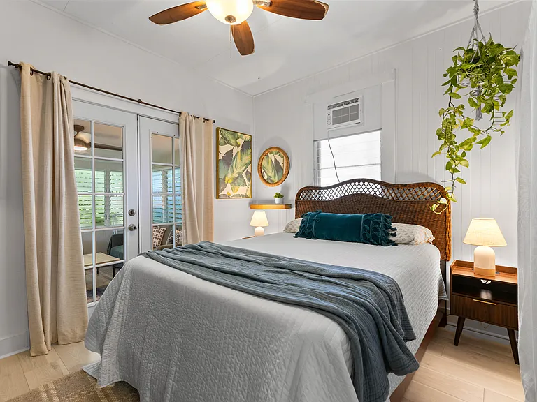 Front bedroom with queen bed, side tables, dresser, AC, ceiling fan, window and large closet with built-in shelving. French doors open to enclosed lanai.