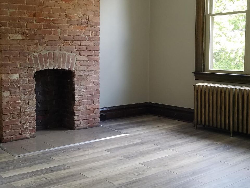Living room with new laminate flooring, exposed brick fireplace.