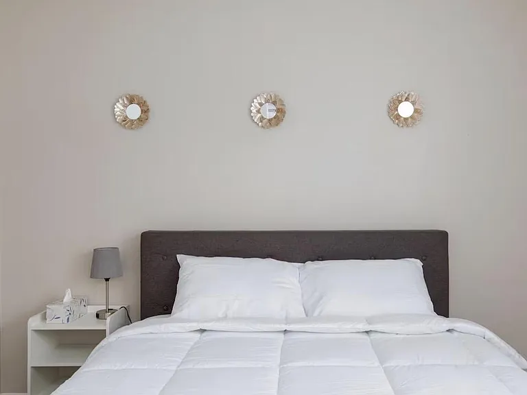 Neatly furnished sleeping area with a comfortable bed, upholstered headboard, and convenient nightstand lighting.