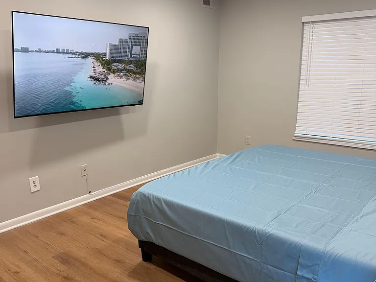Furnished bedroom with hardwood-style floors, recessed lighting, window blinds, and a wall-mounted TV for easy relaxing.