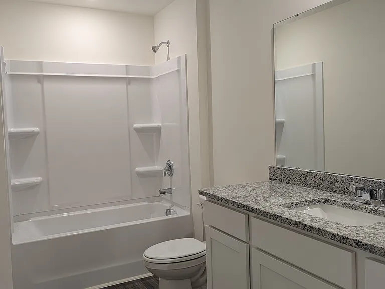 Primary bath with granite countertops, tub/shower, LVP flooring and adjoing walk-in closet