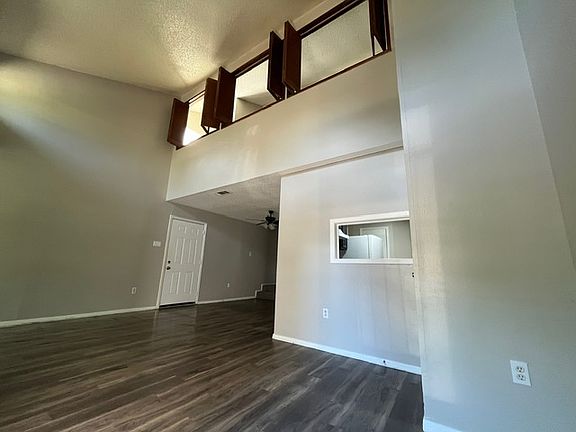 Another view of the living room on the first floor, laminate flooring, kitchen window, and large wooden windows upstairs.