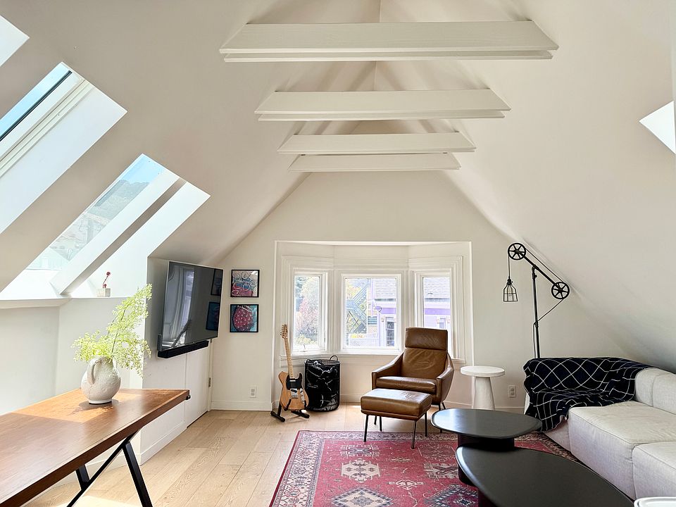 Open concept kitchen, dining, and living space. Bay windows look out onto a quiet slow street (Page Street).