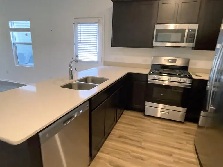 Stainless steel appliances (gas stove), quartz countertops, and refrigerator included.