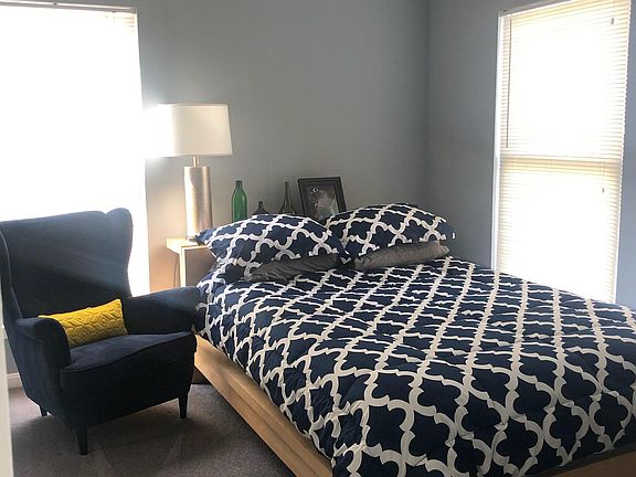 Sunny bedroom with Queen bed and comfy chair. Crown moulding, fresh paint, and a sliding door closet.