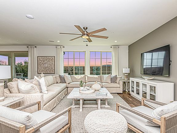 Entertain with ease in your spacious gathering room shown with an overhead fan and large windows.