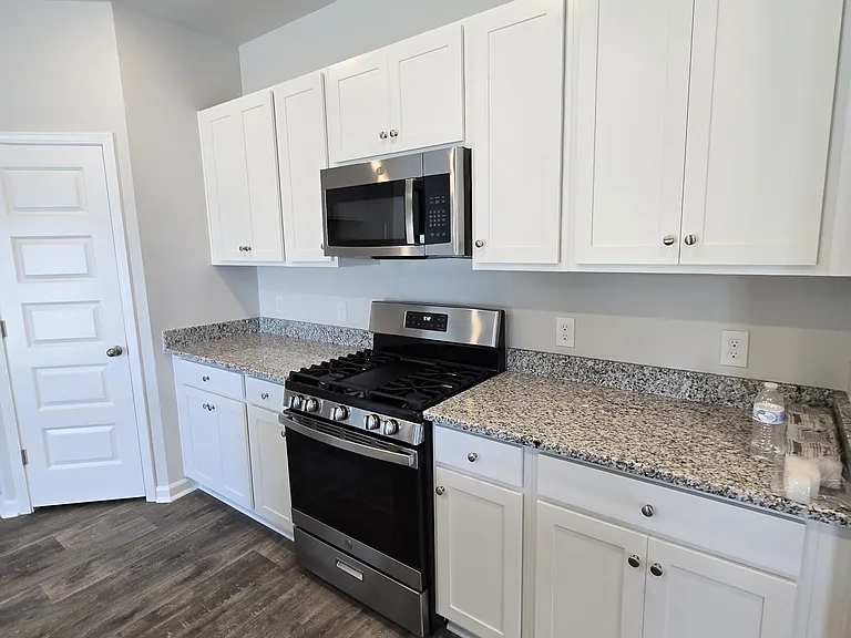 White kitchen cabinets with granite countertops and new appliances