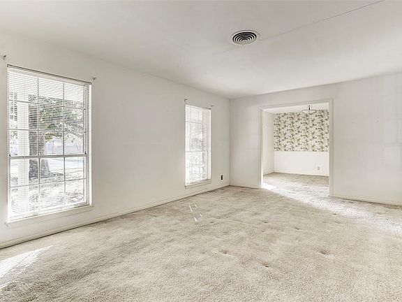 Living area with a view of dining room. Original hardwood floors under carpet.