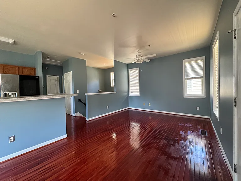 This is the living room. The open floor plan provides a spacious and connected feel, with deep red hardwood floors running throughout