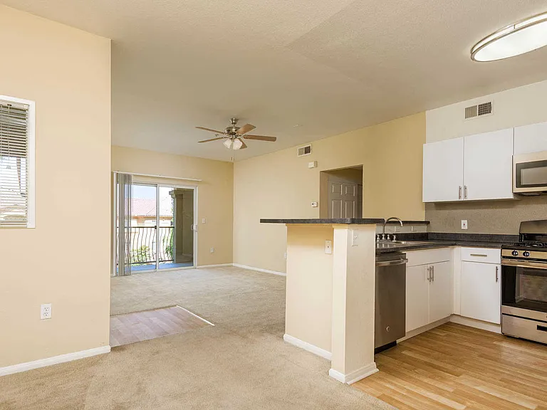 Kitchen and Carpeted Living Room with Balcony
