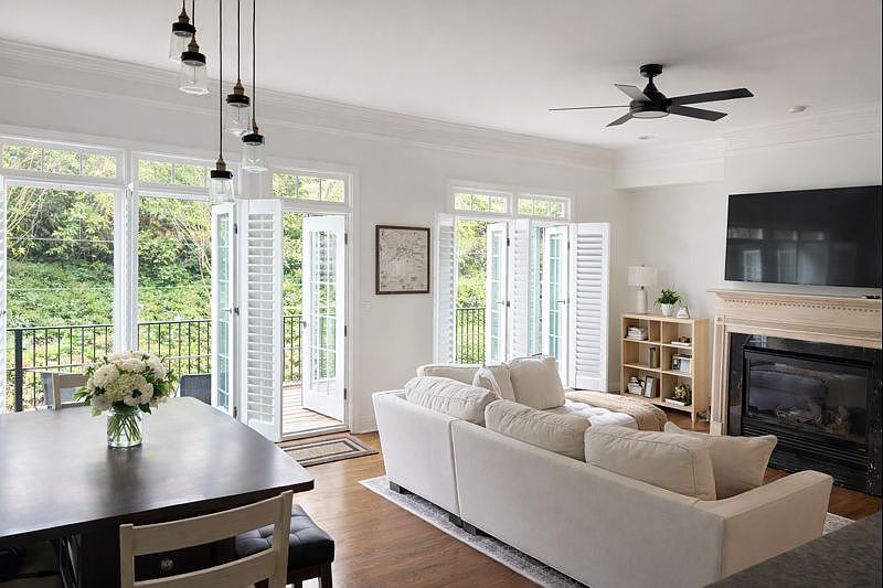 Open-concept living area with hardwood floors, high ceilings and abundant natural light. Access to a half-bath and a patio.