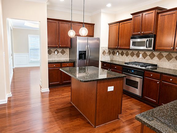 Chef-inspired kitchen showcasing a new cooktop, rich cherry wood cabinets, built-in microwave, and stainless steel appliances.