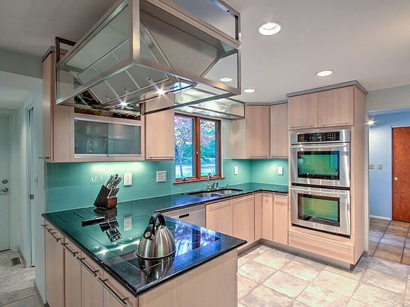 Kitchen has modern cabinets in a light finish, many with frosted glass stainless contemporary handles. 