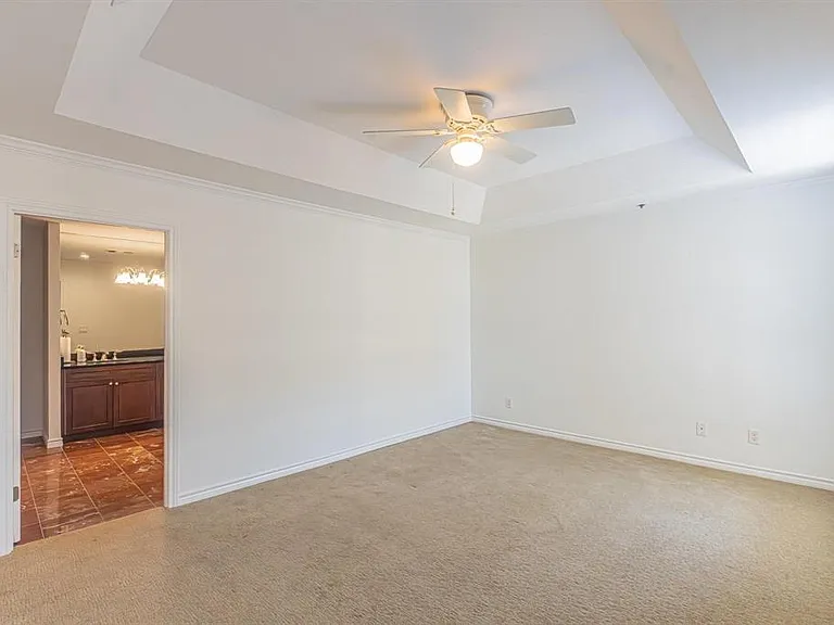 Spacious room featuring a tray ceiling with crown molding, ceiling fan, carpet flooring, and white window blinds