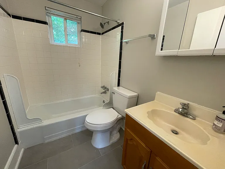 Tile bathroom with black tile accent. All toilets are water efficient for controlling cost