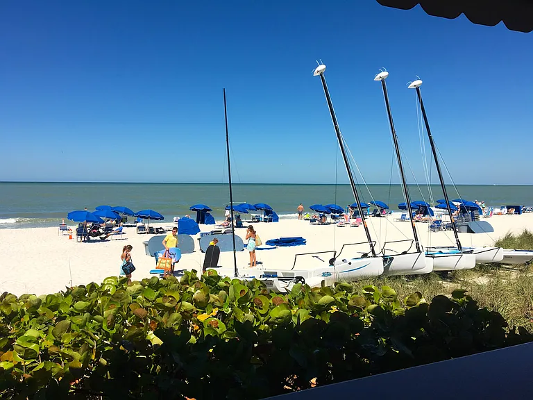 Private beach with free amenities including chairs, tables, umbrellas, cabanas, sailboats, kayaks, paddleboards, cornhole, showers, and restrooms