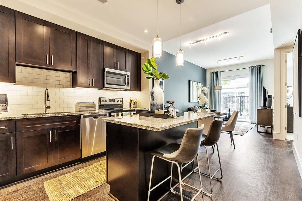 Large kitchen island with hardwood flooring and dark cabinets