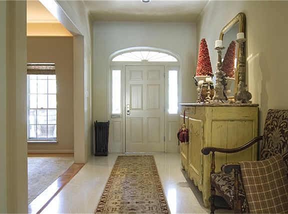  The welcoming, light-filled foyer has high ceilings and connects the dining room (a portion of which is seen at left) with the great room at the rear of the house. Note pretty side- and fan-lights at door and calming pastel wall colors.