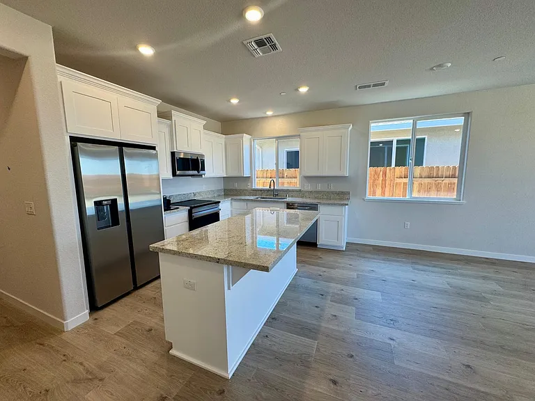 Great room with white cabinets and granite counter top Kitchen including modern appliances