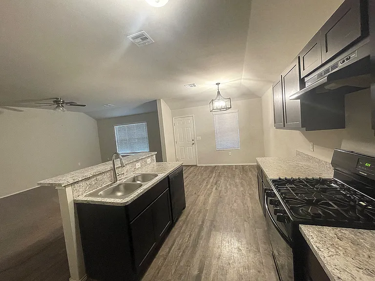 Stove, cabinets, dishwasher and backdoor that leads to the backyard