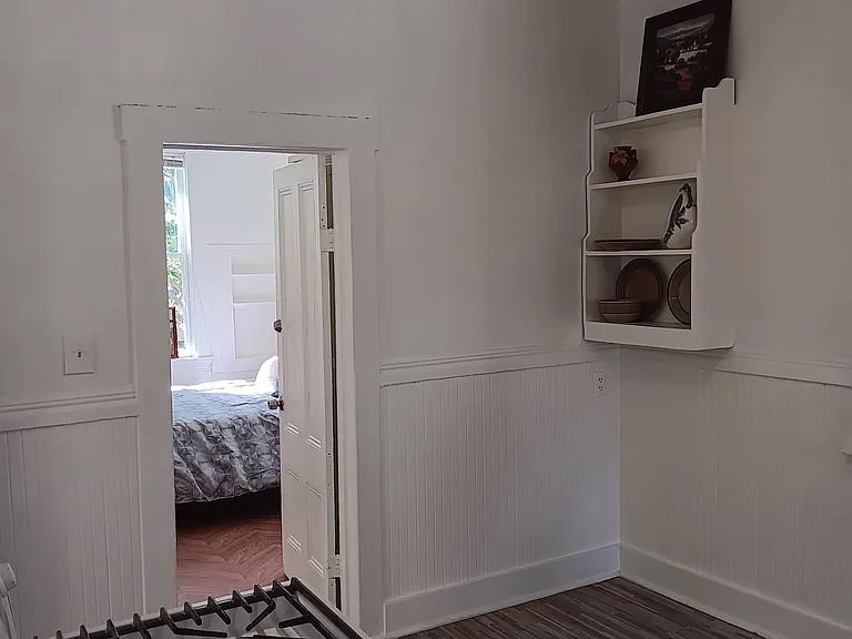 Kitchen with stove and corner shelves w/ open door to 1st bedroom