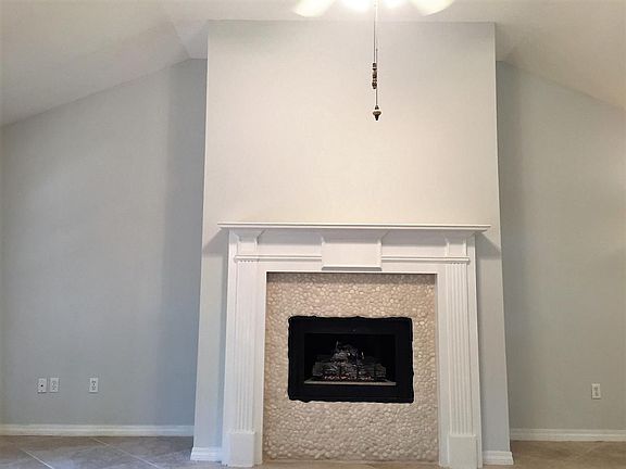 The gas fireplace in the living room featuring 15 foot ceili