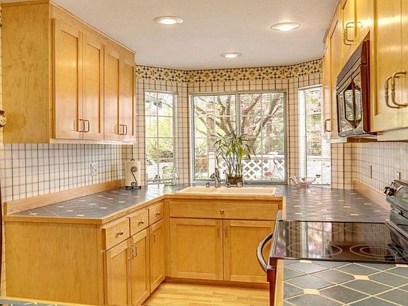 Updated cooks kitchen with attractive wood cabinets, tile counters, bay window, and newer appliances.