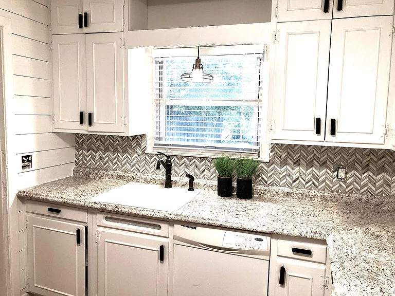 Large renovated kitchen with glass tile backsplash and shiplap walls. New appliances.