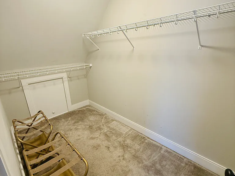 Master bedroom walk-in closet with two luggage racks.