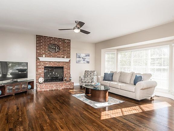 Great room with triple bay window and floor-to-ceiling brick woodburning fireplace