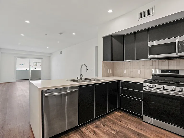 Open-Concept Kitchen with Stainless-Steel Dishwasher, Stove, and Microwave Oven
