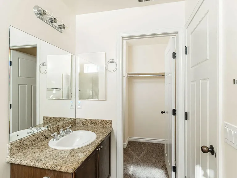 Shared bathroom with granite slab vanity top and upgraded fixtures at The Nines Townhomes in Escondido, California.