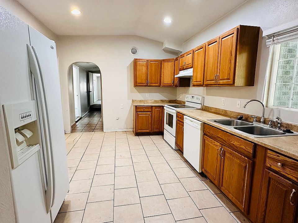 Spacious kitchen with sleek tile flooring, modern wooden cabinets, and ample natural light from large windows.