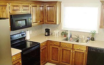 Kitchen with black appliances, tile back splash, cherry cabinets & tile floors