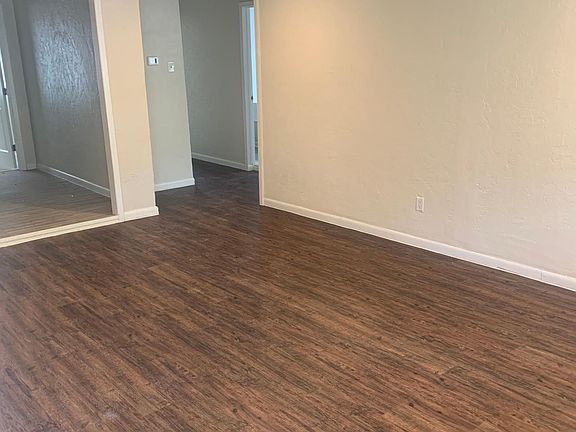 View from front door of living room. To the left is kitchen. To the right is a hall with bathroom and 2 of the bedrooms.