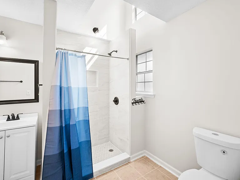 Updated bathroom with tiled walk-in shower, vanity storage, and window for natural light and ventilation.