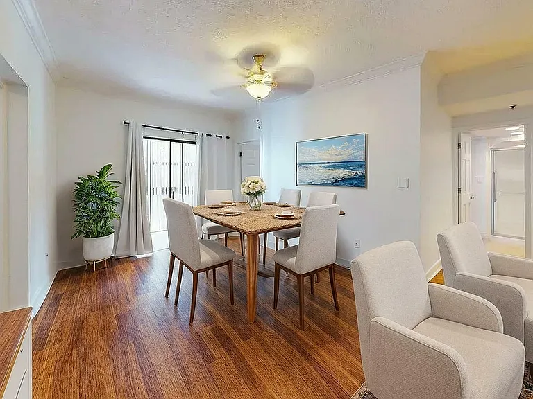 Bright and inviting dining area with elegant wooden flooring, a modern table set, and abundant natural light from large sliding doors.
