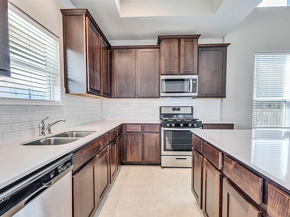 Kitchen has a fridge and a gas stove/oven