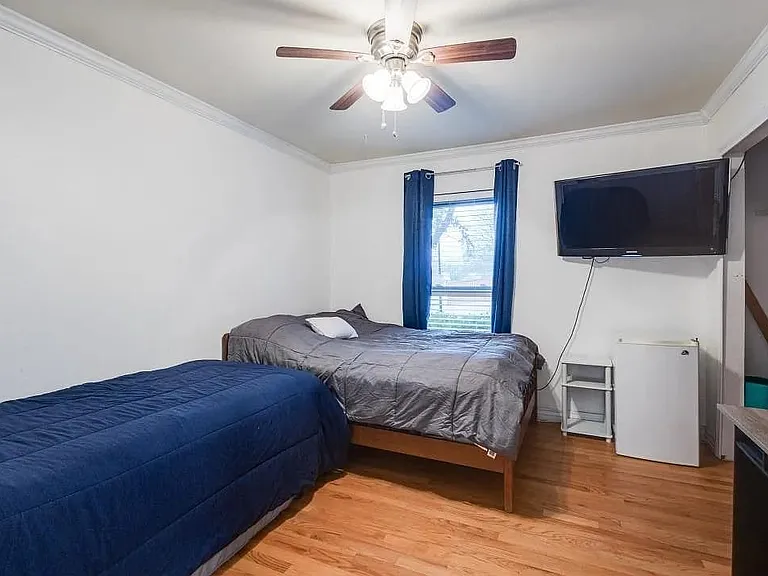 Hardwood-style flooring throughout this room with a ceiling fan, crown molding, and a window with blinds
