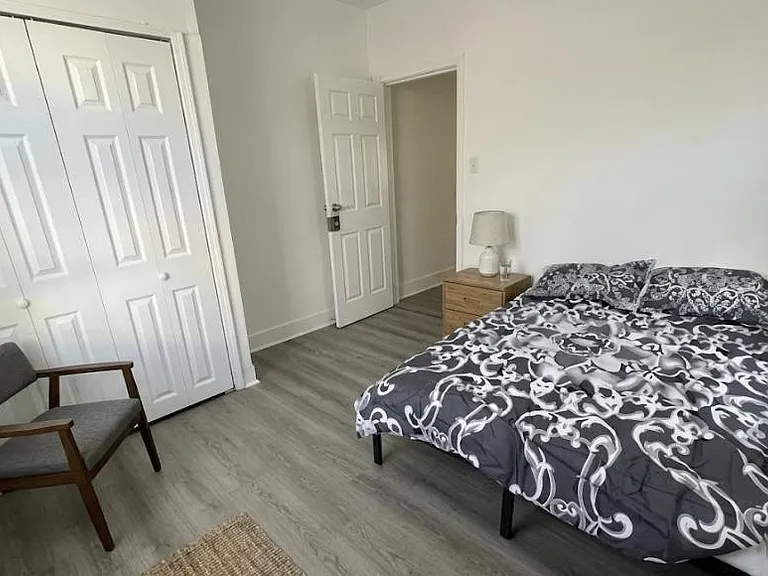 Furnished bedroom with a full bed, nightstand and lamp, plus a large double-door closet and easy-care flooring.