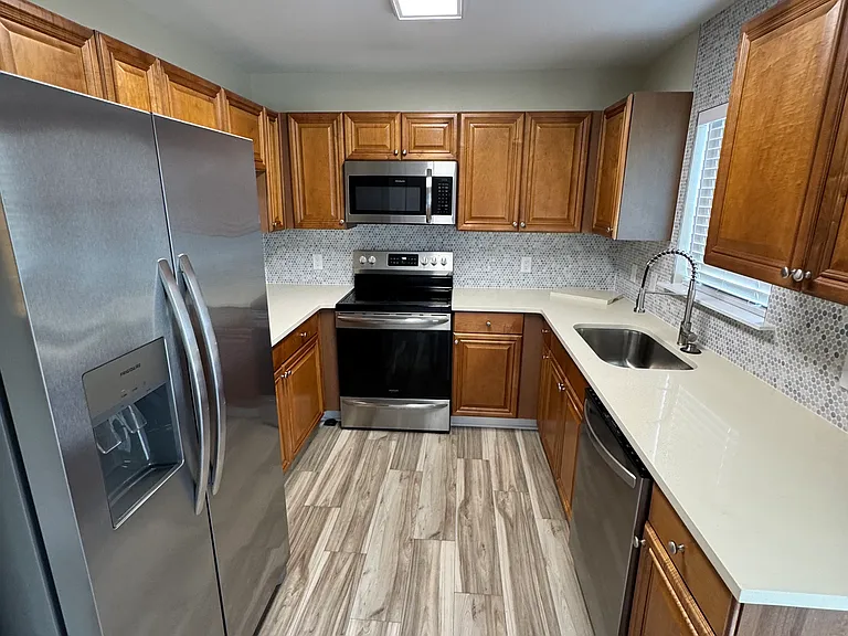 Kitchen with quartz counters, stainless steel appliances, & custom backsplash.