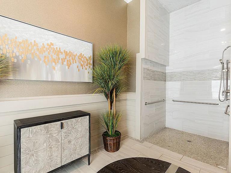 Elegant bathroom featuring modern walk-in shower, stylish artwork, and lush green plant for a touch of nature.