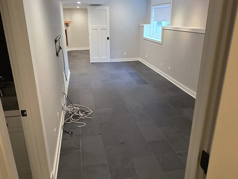 View from basement bedroom into long open living area.