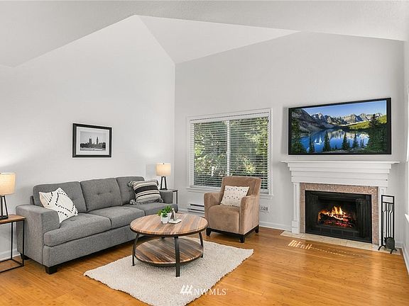 Spacious and open living room features vaulted ceilings, wood burning fireplace and bamboo hardwood floors. 