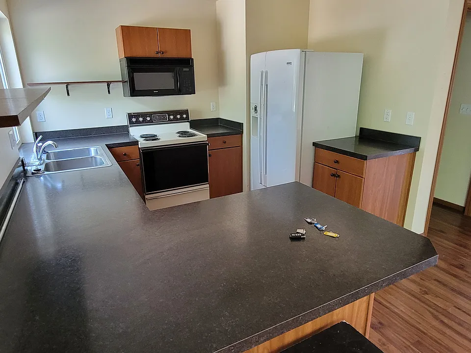 Kitchen with oven, fridge, microwave, and garbage disposal.