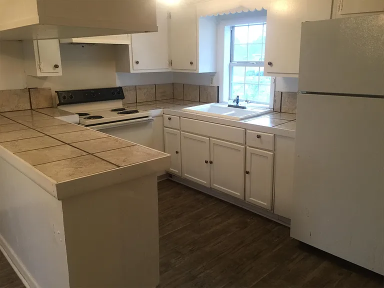 Kitchen with new tile countertops, new sink, vinyl flooring. View from the living room