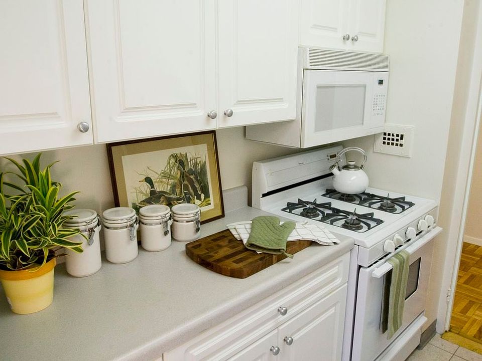 Kitchen with white countertop, white cabinetry, white appliances and hard surface flooring