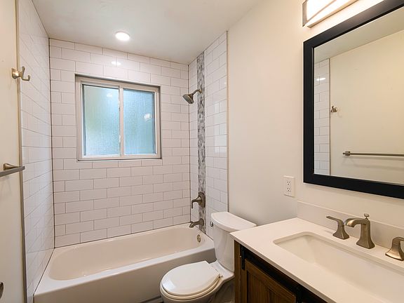 Full bathroom upstairs with modern tile surround and tile flooring.